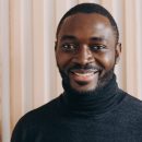 Portrait of happy cheerful african american man smiling at camera, expressing positive emotions. Headshot of handsome dark-skinned guy in grey poloneck sweater posing for indoor photo,