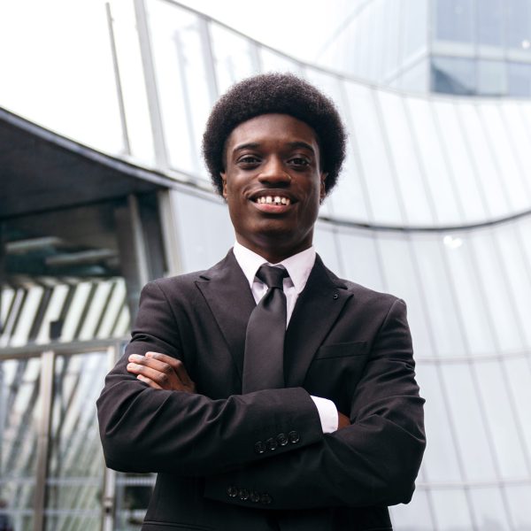 Confident african businessman with crossed arms, corporate setting.